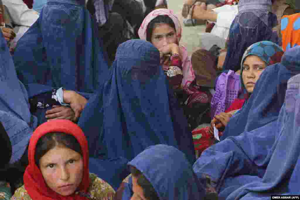 Afghan women with children wait to receive a donation of meat from a sacrificed animal on the occasion of the Muslim festival of Eid al-Adha in the Fayzabad district of Badakhshan Province on June 28.