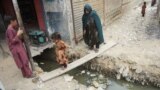 An Afghan girl and her mother cross an open sewer at a refugee camp in Karachi. Pakistan has said that it plans to deport over 1 million Afghans living in the country who do not have valid residency documents. 