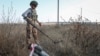 A member of the Demining of Ukraine NGO works near a piece of a MLRS shell in a field near the town of Derhachi in the eastern Kharkiv region. 