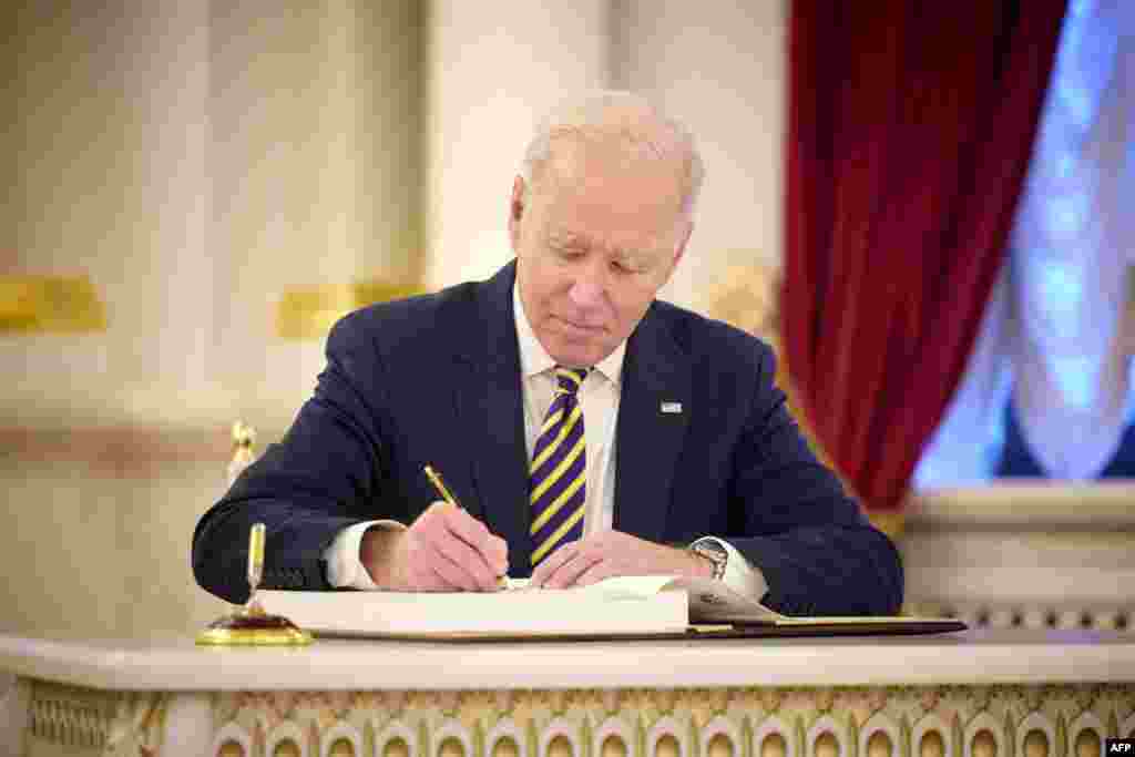 Președintele american Joe Biden semnează în cartea de oaspeți a palatului prezidențial.&nbsp;