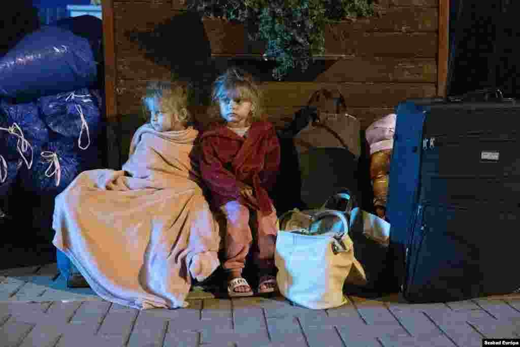 Children huddle up for warmth as they try to sleep on the pavement with their belongings in the Hungarian town of Kocs, about 70 kilometers west of Budapest, on August 22. They were evicted from a privately owned shelter after a Hungarian government directive limited free shelter to refugees from conflict-affected regions of Ukraine.