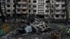 The hulk of a destroyed car lies next to a damaged residential building following a missile strike in Kyiv on December 13.
