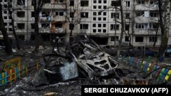 The hulk of a destroyed car lies next to a damaged residential building following a missile strike in Kyiv on December 13.
