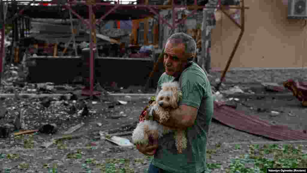 Muškarac drži psa ispred kafića uništenog u ruskom vazdušnom napadu u gradu Harkivu na sjeveroistoku Ukrajine 22. maja.