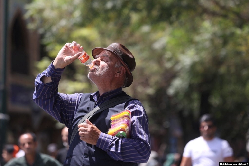 Un uomo beve durante l'ondata di caldo a Teheran.  La chiusura a livello nazionale di uffici, banche e scuole ha lo scopo di risparmiare energia, poiché la rete elettrica mal mantenuta del paese lotta con la domanda più alta del solito.