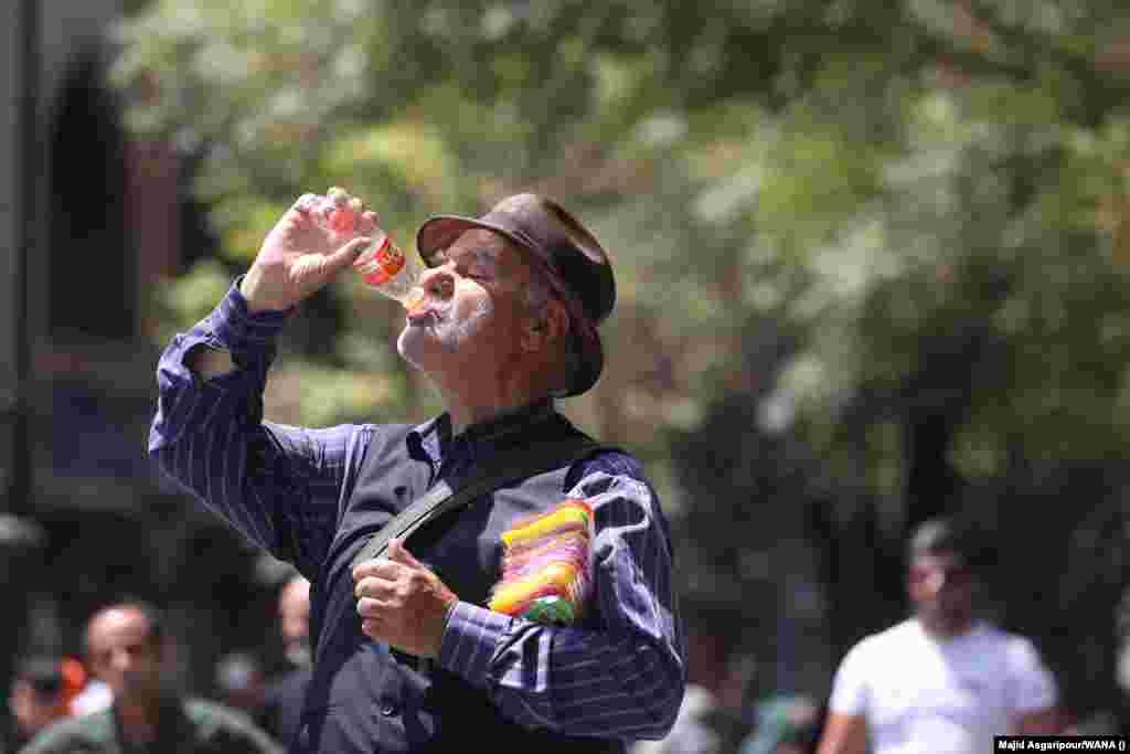 A man drinks during the heat wave in Tehran. The nationwide shutdown of offices, banks, and schools is aimed at conserving energy as the country&#39;s poorly maintained power grid struggles with the higher-than-usual demand.