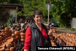 Зоя Гиоргадзе, которая десятилетиями продаёт керамику на обочине дороги в Шроше, стоит у своего прилавка