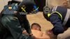 Маскирани испански полицаи задържат един от заподозрените.