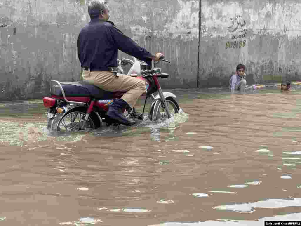 Një polic pakistanez kalon me motoçikletë nëpër ujë në një zonë të përmbytur si pasojë e reshjeve të dendura në Lahore.