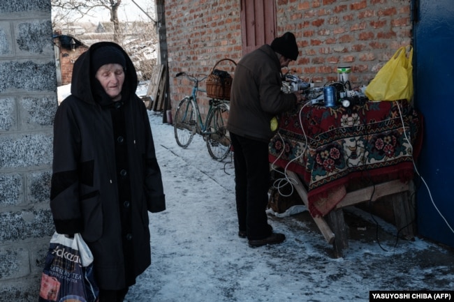 Az önkormányzat által üzemeltett kültéri generátorról töltik a lakosok a telefonjaikat és az akkumulátoraikat Szeverszkben 2023. február 17-én