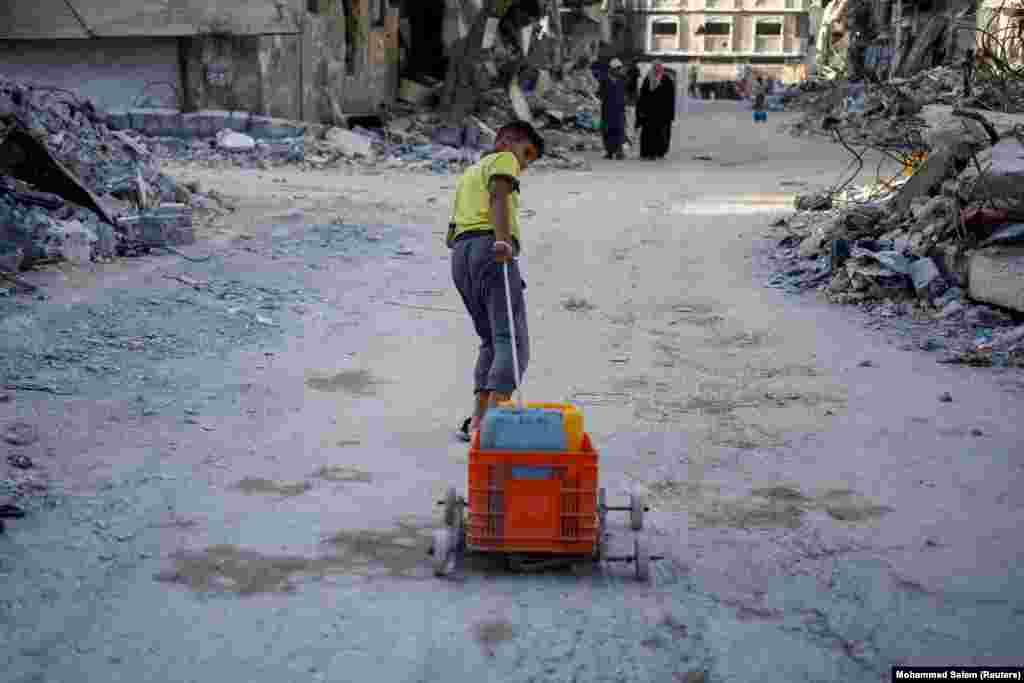 Një djalë palestinez tërheq me një karrocë të improvizuar enë të mbushura me ujë mes mungesës së madhe të ujit, Han Junis, 3 qershor 2024.