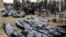 Поліцейські поруч із тілами загиблих під час російської окупації Бучі на місцевому кладовищі, квітень 2022 року