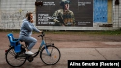 A local resident cycles by a recruitment advert for the Ukrainian Army in the Dnipropetrovsk region (file photo)