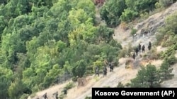 This photo taken by a drone on September 24 shows a group of armed men walking along a mountain path near the Banjska monastery in Kosovo.