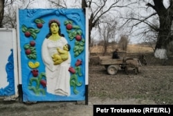 A man rides in a donkey cart past a brightly painted bus stop in the Zhetysu region.