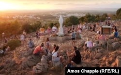 Hodočasnici se okupljaju oko statue Djevice Marije na mjestu gdje je nekoliko djece prijavilo ukazanje u ljeto 1981.