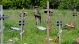 Вооруженный военный дежурит на кладбище во время захоронения останков российских военнослужащих. Луганск, подконтрольная России часть Украины, 18 мая 2023 года
