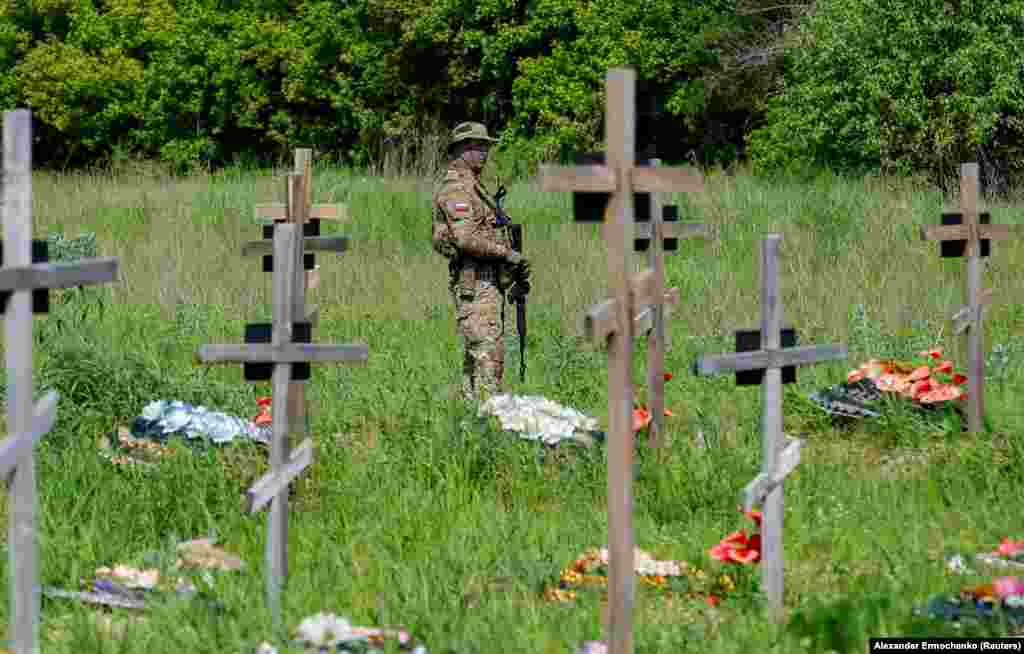 Узброены салдат на варце падчас пахаваньня 60 расейскіх вайскоўцаў і трох мірных жыхароў на могілках у Луганску ва Ўкраіне, якая знаходзіцца пад кантролем Расеі.