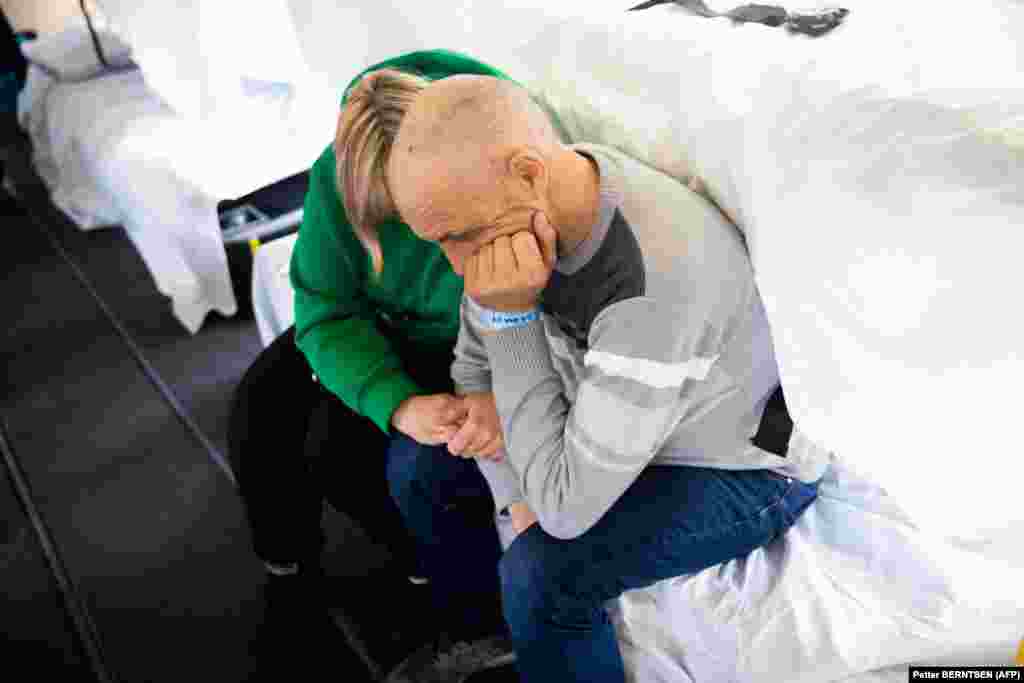 A woman comforts a wounded Ukrainian soldier as he waits to be transported out of Poland. The Norwegian authorities estimate that half a million people are deprived of medical care in Ukraine every month.