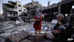 Palestinska obitelj se priprema za iftar, usred ruševina svoje obiteljske kuće, prvog dana svetog muslimanskog mjeseca posta ramazana, u Deir el-Balahu u središnjem Pojasu Gaze 11. marta 2024., usred stalnih borbi između Izraela i militantne skupine Hamas. 