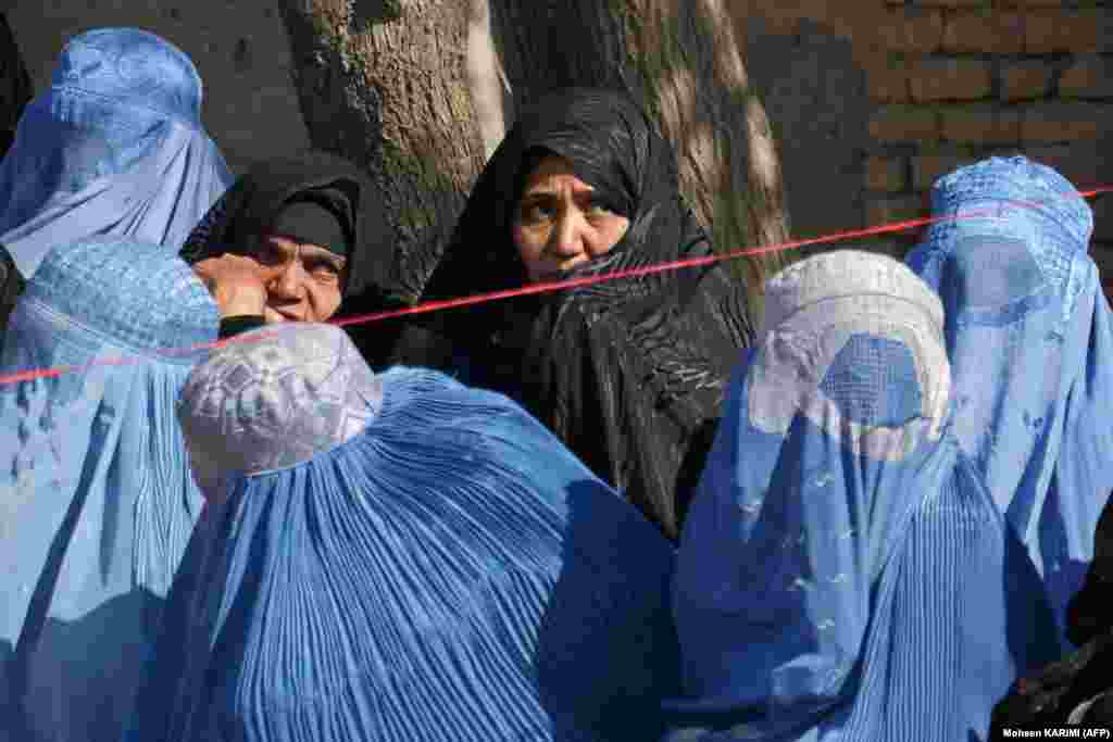 Afghan women wait to receive food aid in Herat.