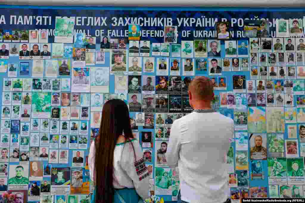 &nbsp;People look at a wall honoring fallen defenders of Ukraine.