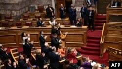 Членове на гръцкото правителство аплодират по време на гласуването в парламента за еднополовите бракове в Атина.