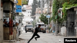 Një palestinez duke ikur teksa trupat izraelite kryejnë një bastisje në Nablus, në Bregun e pushtuar Perëndimor. 13 qershor 2023.
