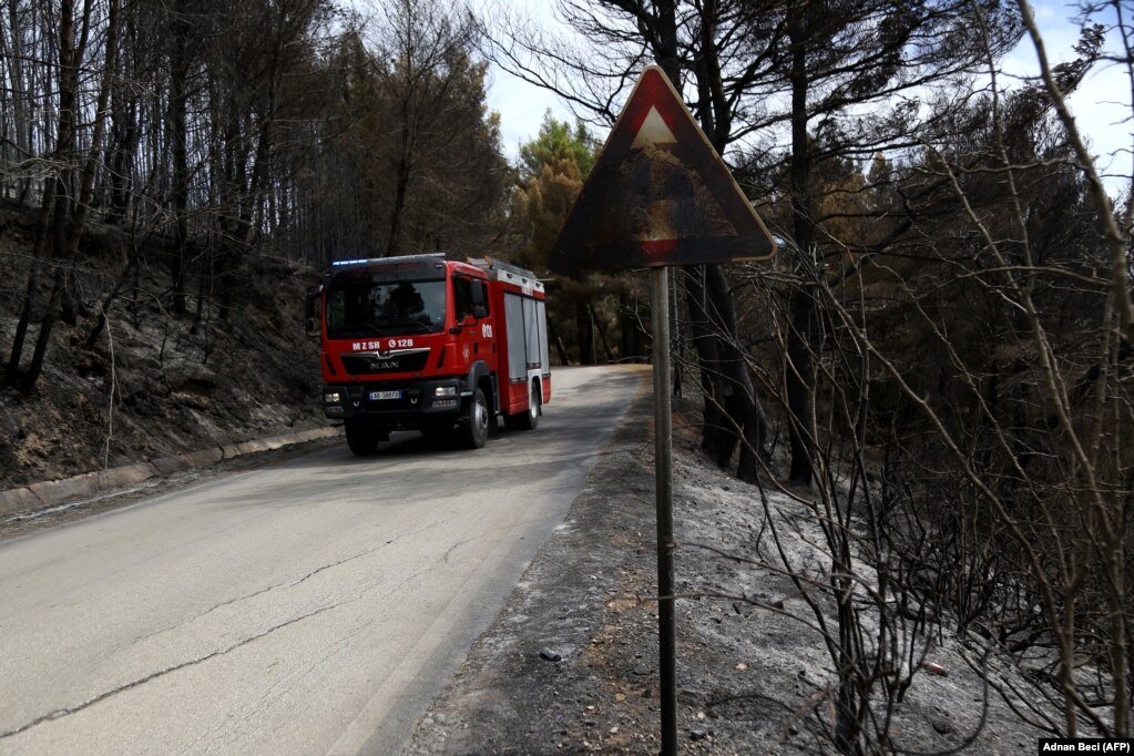 Një kamion zjarrfikës duke qarkulluar mes një zone të shkrumbuar afër qytetit të Fierit.