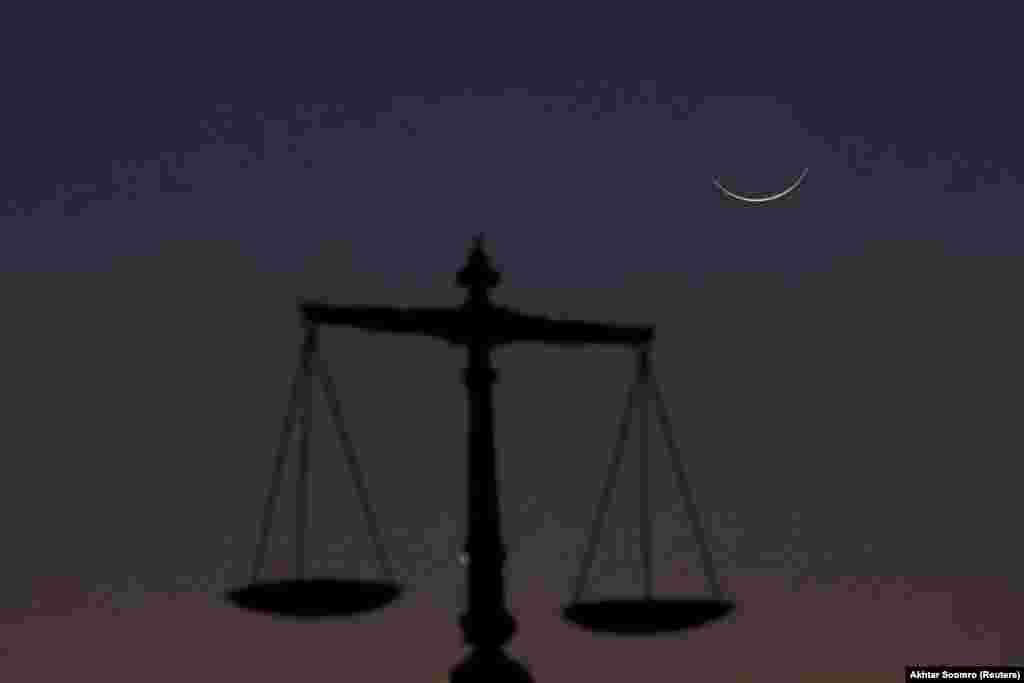 The crescent moon is seen with a scale at the Sindh High Court in Karachi on March 11.