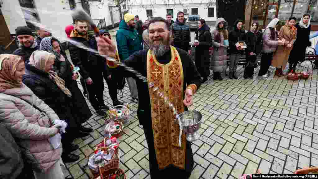 Священник УПЦ (МП)&nbsp;освячує водою вірян та їхні великодні кошики біля Воскресенської церкви на території Києво-Печерської лаври