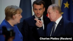 Former German Chancellor Angela Merkel (left) talks with Russian President Vladimir Putin (right) and Fench President Emmanuel Macron looks on. (File photo)