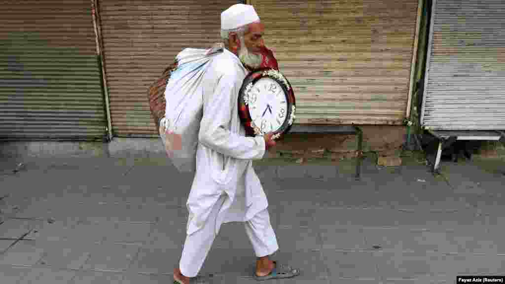 Čovjek koji nosi zidne satove na prodaju šeta zatvorenim mjenjačnicama u Peshawaru, Pakistan.