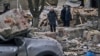 Луѓе пред оштетена зграда во Словјанск во Украина на 27 март 2023