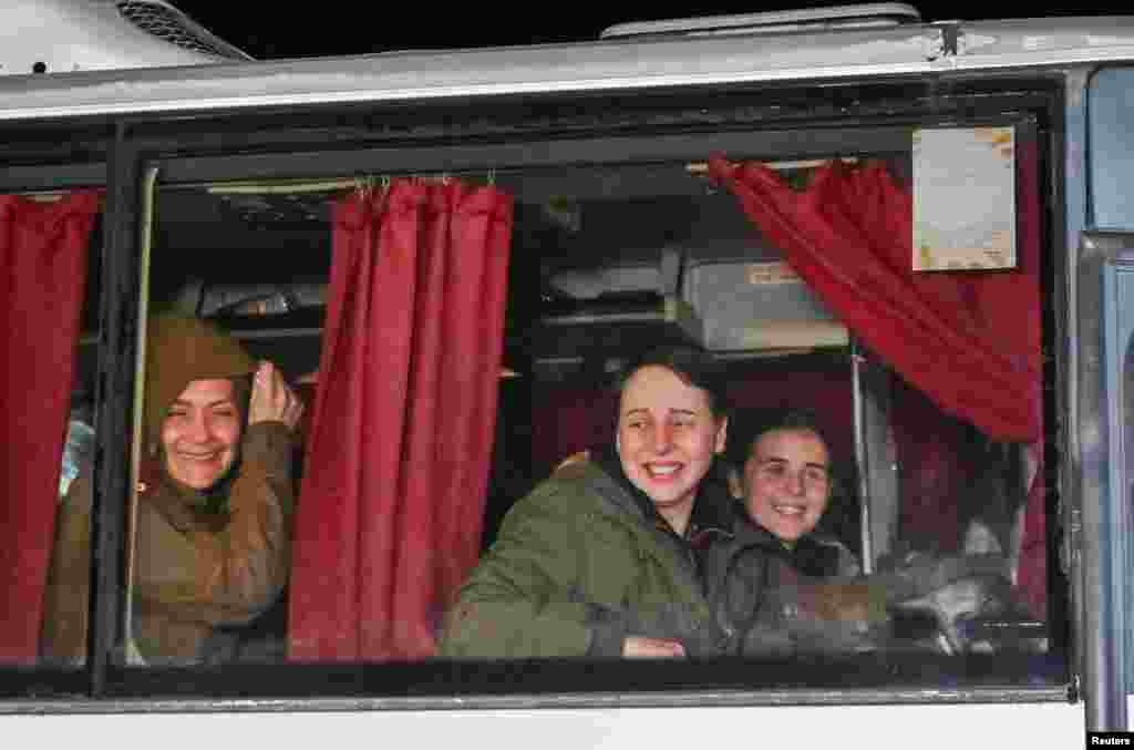 Ukrainian women prisoners look out of a bus window as they arrive to a crowd of family and supporters in Zaporizhzhya on October 16, 2022, after months in Russian captivity.