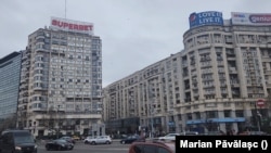 Piața Victoriei, centrul Capitalei. De pe blocurile înalte, locuitorii sunt ademeniți, prin panouri uriașe, care fac reclamă la pariuri sportive. În România sunt aproape 700 de case de pariuri.