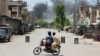 Men watch as smoke rises following an explosion after militants attacked an army base in Pakistan's northwestern city of Bannu on July 15.