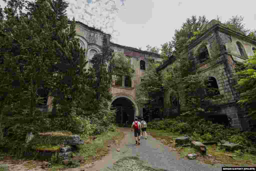 Tourists walk through the abandoned settlement of Akarmara in the Georgian breakaway region of Abkhazia on July 21.&nbsp; It was founded for mining operations in 1938, with many of its buildings constructed in the 1940s and 1950s by German prisoners of war.