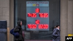 People walk past a currency exchange office in Moscow in February.