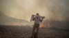 Muškarac koristi peškir preko lica dok pokušava ugasiti vatru, u blizini primorskog odmarališta Lindos, na otoku Rodosu u Egejskom moru.&nbsp;