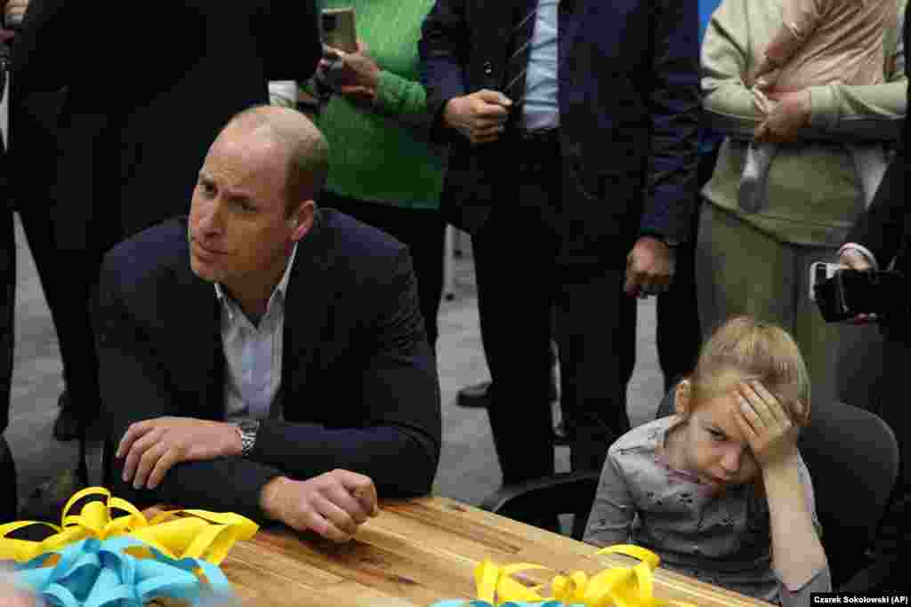 A young girl holds her head as Britain&#39;s Prince William visits an accommodation center for Ukrainians who fled the war, in Warsaw on March 22.