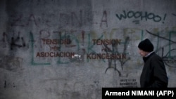 Një burrë duke kaluar pranë një muri ku është shkruar "Tension për asociacion", në Prishtinë. Fotografi ilustruese.