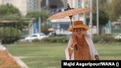 A woman carries a parasol as she tries to stay cool amid an &quot;unprecedented&quot; heat wave in Tehran on August 2. The capital hit 37 degrees Celsius, while other parts of the country saw temperatures hit 40 degrees.<br />
<br />
The extreme heat comes as rising anger over a range of economic issues as well as water outages has led to&nbsp;<strong><a href="https://www.rferl.org/a/iran-water-protests-sistan-baluchistan/32529908.html">protests</a></strong> against the government&#39;s mismanagement of resources.<br />
<br />
&nbsp;