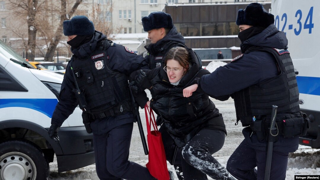 Trei polițiști rețin o femeie la o adunare din Moscova în memoria lui Alexei Navalnîi pe 17 februarie 2024.