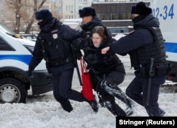 Trei polițiști rețin o femeie la o adunare din Moscova în memoria lui Alexei Navalnîi pe 17 februarie 2024.