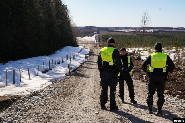 Finnish border guards stand near border fence with Russia in Pelkola, Finland, on April 14.