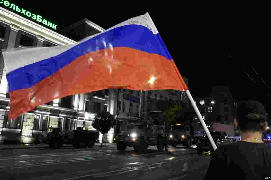 A man waves the Russian flag as members of the Wagner group pull out from the headquarters of the Southern Military District in Rostov-on-Don to return to their base late on June 24.