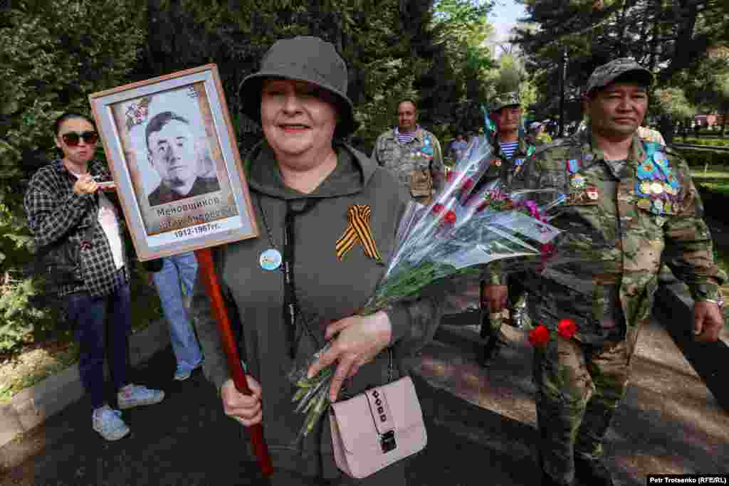 Женщина несёт портрет родственника-ветерана, Алматы, 9 мая 2023 года