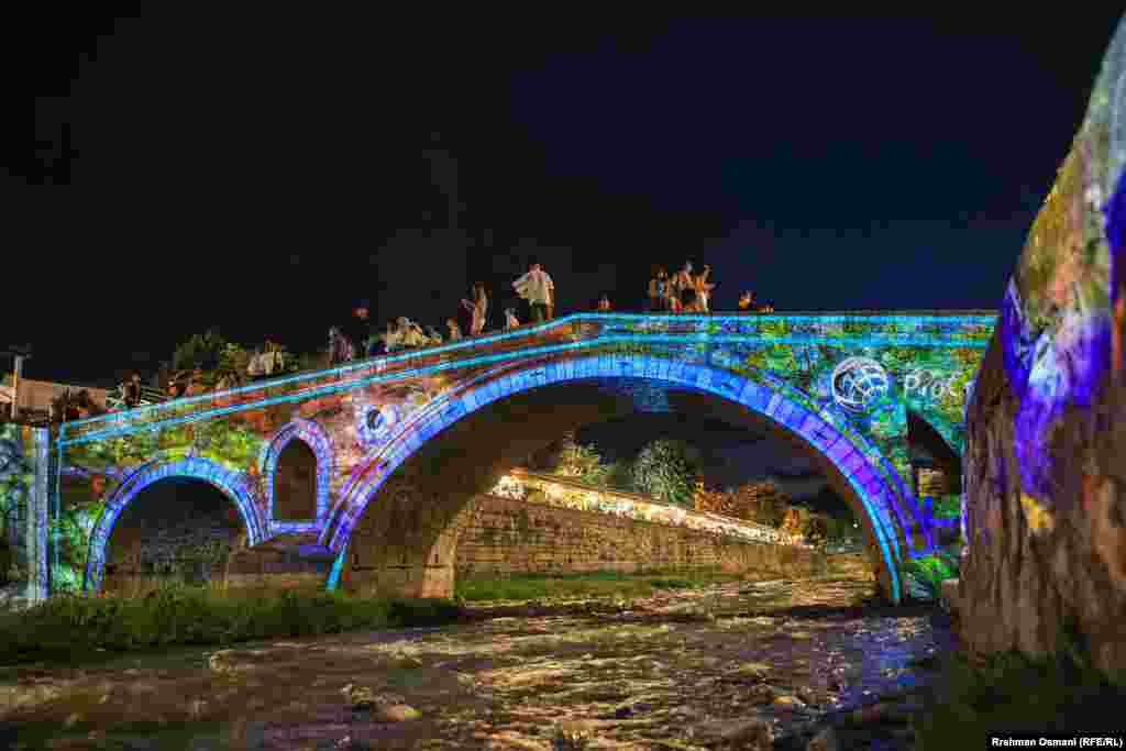 Ura e ndriçuar mbi Lumbardhin e Prizrenit gjatë Dokufestit.&nbsp; Çdo vit, mijëra persona nga Kosova dhe e mbarë bota mblidhen në Prizren për të ndjekur nga afër Festivalin Ndërkombëtar të Filmit të Shkurtër dhe Dokumentar, DokuFest. &nbsp;