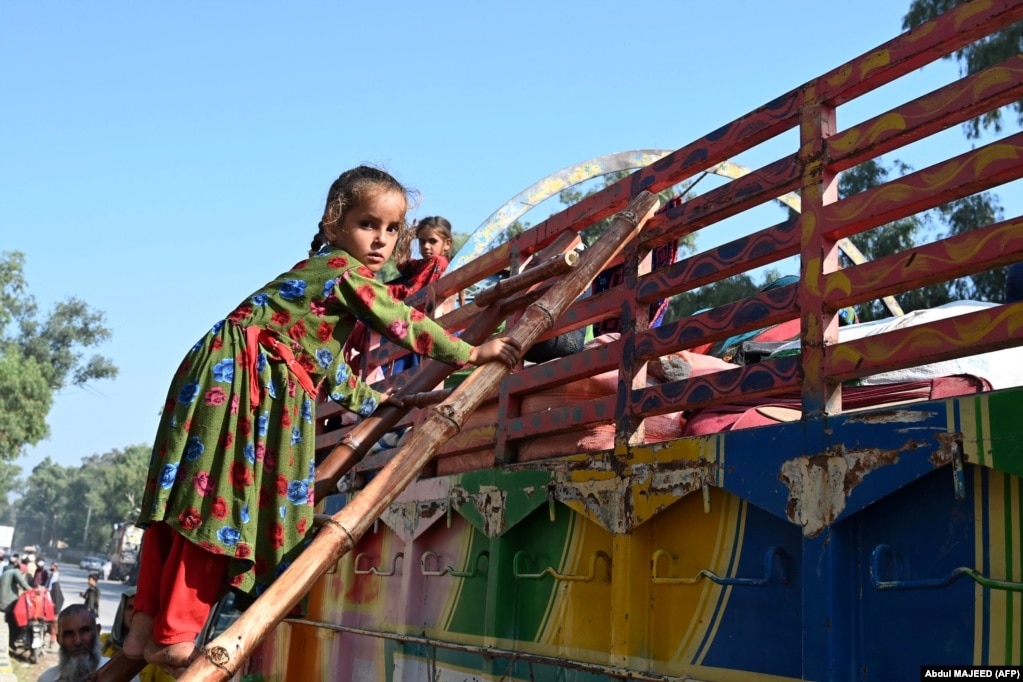 An Afghan girl living in Pakistan climbs a ladder onto a truck to begin her journey back to Afghanistan.